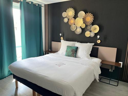 a bedroom with a large bed with white sheets at Hotel Le Gambetta in Bergerac