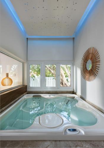 a jacuzzi tub in a room with windows at So White Beach Resort in Ayia Napa