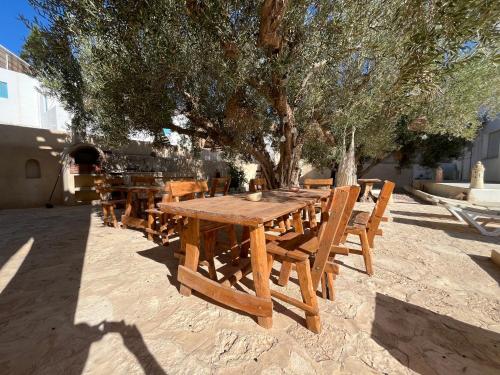 a wooden picnic table and chairs under a tree at Dar Younes in Houmt Souk