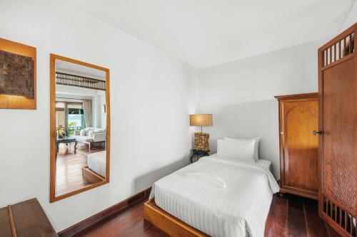 a bedroom with a bed and a mirror at The Kala in Amphoe Koh Samui