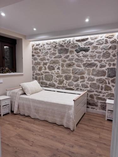 a bedroom with a stone wall and a bed at La casa de cuatro caminos in Arenas de Cabrales