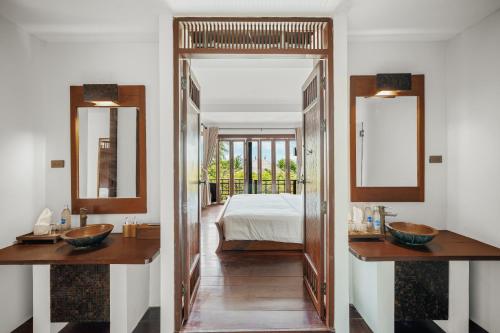 a bathroom with two sinks and a bedroom with a bed at The Kala in Amphoe Koh Samui