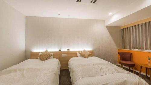 a room with two beds and a table and a chair at Centrale Hotel Kyotango in Kyotango