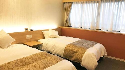 a hotel room with two beds and a window at Centrale Hotel Kyotango in Kyotango