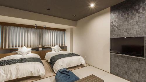 a bedroom with two beds and a flat screen tv at Centrale Hotel Kyotango in Kyotango