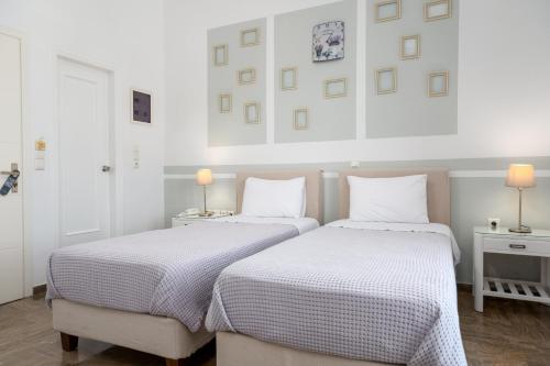 two beds in a white bedroom with two lamps at Hotel Oasis in Parikia