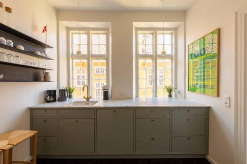 a kitchen with a sink and two windows at Lovely Apartment Overlooking King's Garden in Copenhagen