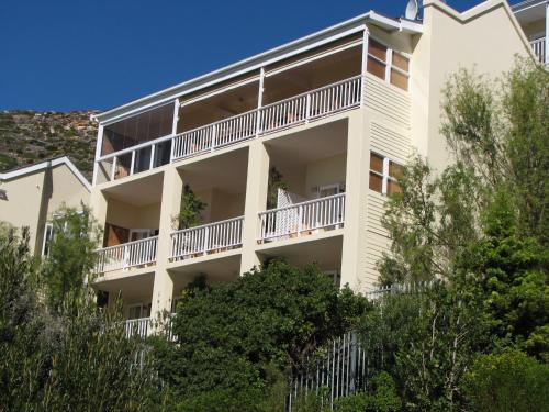 an apartment building with balconies and trees at Albatross Guest House in Simonʼs Town