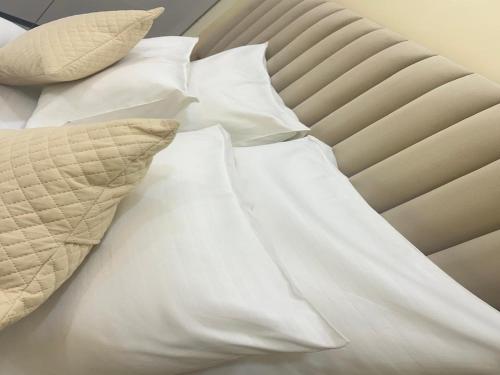a bed with white sheets and pillows on it at Akshay premium suites1 BHK Serviced Apartments Near Artemis Hospital Sector 52 in Gurgaon