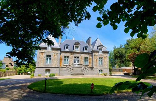 an old house with a grassy yard in front of it at Manoir Le Castel & Villa Beaumaris in Saint Malo