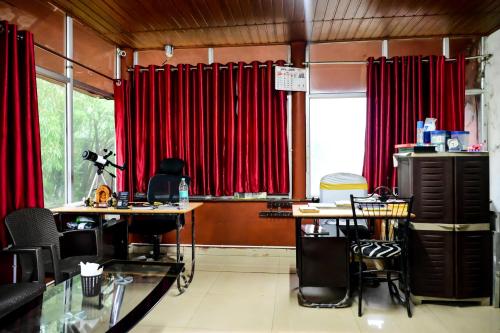 a room with red curtains and two tables and chairs at Kumbles Misty Mount in Attigundi