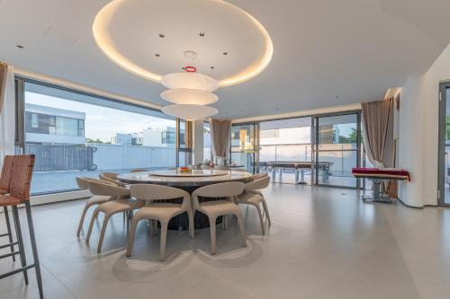 a dining room with a table and chairs and a chandelier at TML-6 bedrooms-independent swimming pool and Luxury KTV room and fitness area and pool table in Ban Huai Yai