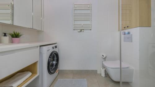 a white bathroom with a washing machine and a toilet at Nexo, Sun & Snow in Puck