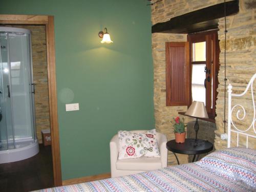a bedroom with a bed and a chair and a window at Casa Carballeira in Villarfernando