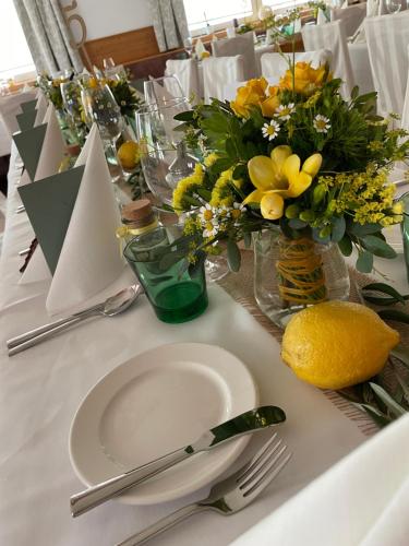 a white table with a white plate and flowers in a vase at Hotel des Glücks - Landhotel Fischl in Sankt Oswald