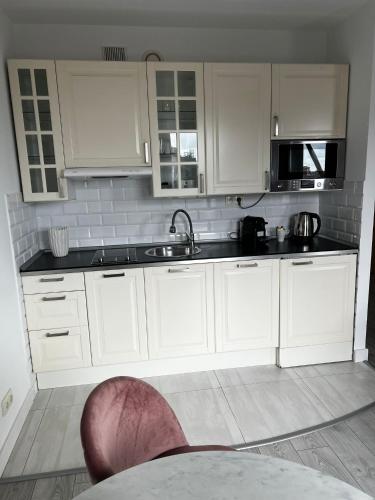 a kitchen with white cabinets and a sink at Silver Apartments in Wrocław
