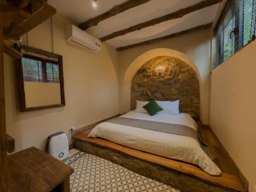 a bedroom with a bed with a stone wall at AMAYA HOME - Lodge, Spa & Restaurant in Hanoi