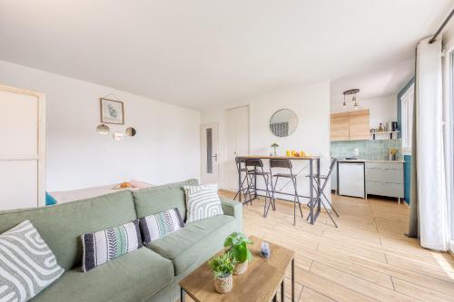 un salon avec un canapé vert et une cuisine dans l'établissement Studio meublé Métro 12, à Aubervilliers