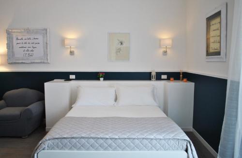 a bedroom with a white bed and a chair at Novecento Dimore di Poesia in Trani