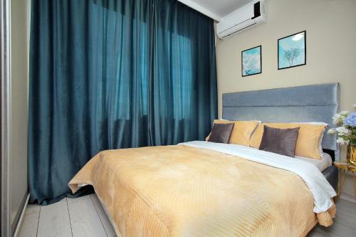 a bedroom with a large bed with blue curtains at Arbat Central Apartment in Almaty