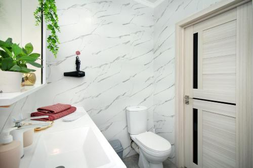 a white bathroom with a toilet and a sink at Arbat Central Apartment in Almaty