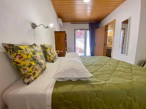 a bedroom with a large green bed with pillows at Casa de Azzancha in Azinhaga