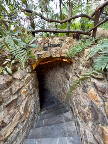 a stone tunnel in a stone wall with stairs at AMAYA HOME - Lodge, Spa & Restaurant in Hanoi