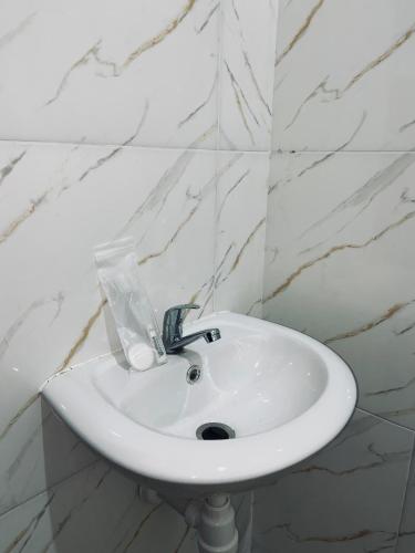 a white sink in a bathroom with white marble walls at Hotel Grand Ansara Mentari in Baturaja