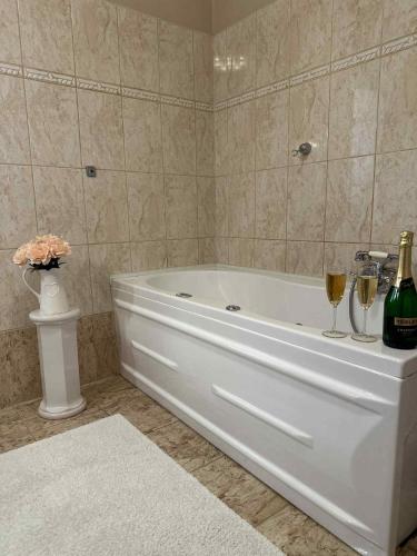 a white tub in a bathroom with two glasses of wine at Vidéki Vendégház in Doboz