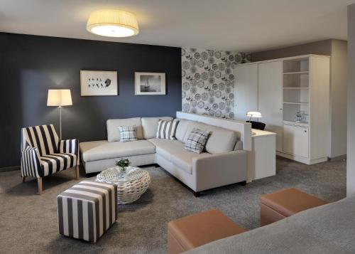 a living room with a white couch and chairs at Hotel Regina Maris in Norddeich