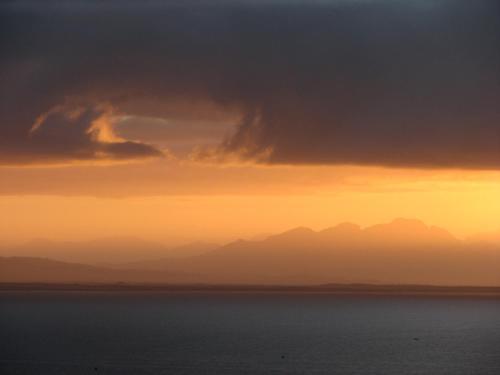 a sunset over the water with mountains in the distance at Albatross Guest House in Simonʼs Town