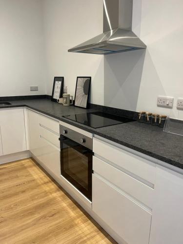 a kitchen with white cabinets and a black counter top at Margate Apartment by The Sea 5 minutes to beach and dreamland in Margate