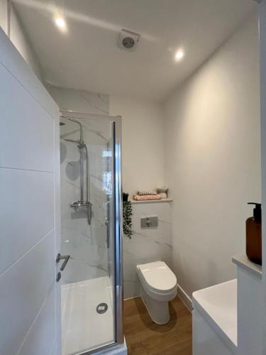 a white bathroom with a shower and a toilet at Margate Apartment by The Sea 5 minutes to beach and dreamland in Margate