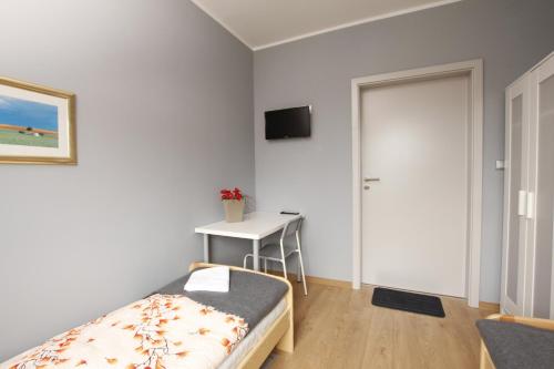 a bedroom with a bed and a table and a door at Hostel w ogrodzie in Grudziądz