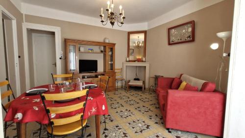 un salon avec une table et un canapé rouge dans l'établissement St Georges de Didonne - MAISON en plein CENTRE-VILLE - PROCHE PLAGE, à Saint-Georges-de-Didonne