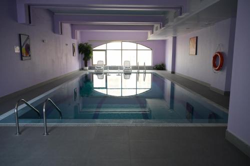 a swimming pool in a building with a large window at Best Western Plus Mahboula in Kuwait