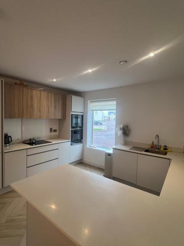 a kitchen with white cabinets and a large window at Stylish SuperKing and King Ensuite Bedrooms in Dublin in Dublin