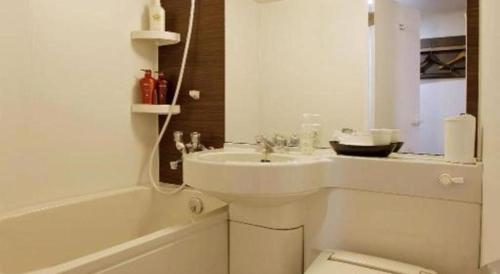 a bathroom with a sink and a toilet and a tub at Hotel Sunoak Kashiwanoha in Kashiwa