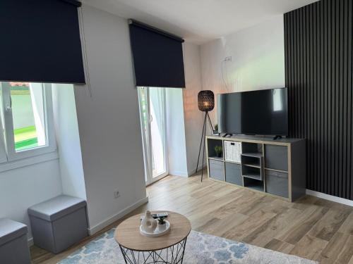a living room with a tv and a table at Apartamentos Porta do Vez Centro Histórico Moderno in Arcos de Valdevez