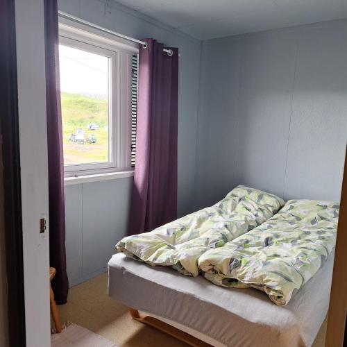 an unmade bed in a bedroom with a window at Grasbakken Panorama in Varangerbotn