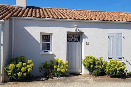 une maison blanche avec une porte et des fleurs jaunes dans l'établissement Haven of peace 2 steps from the sea, à La Tranche-sur-Mer