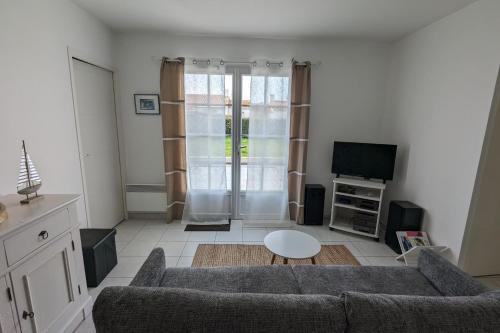 un salon avec un canapé et une télévision dans l'établissement Haven of peace 2 steps from the sea, à La Tranche-sur-Mer