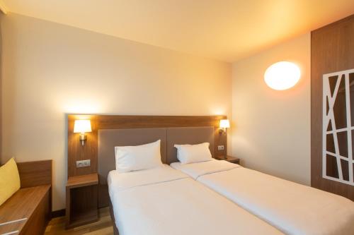 a bedroom with a large white bed with two pillows at Campanile Metz Centre - Gare in Metz