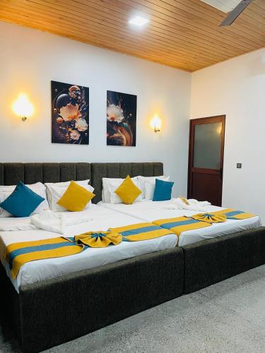 a large bed with yellow and blue pillows on it at The Sanctum in Talaimannar