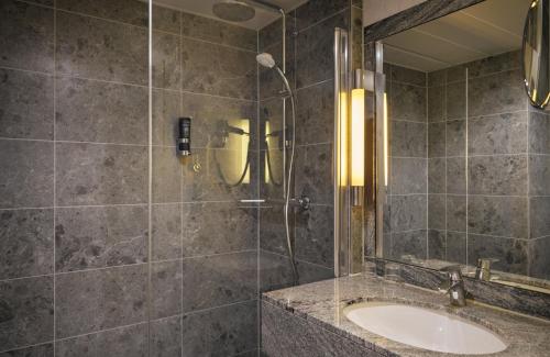 a bathroom with a sink and a shower at Leonardo Royal Hotel Düsseldorf Königsallee in Düsseldorf