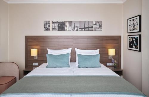 a bedroom with a large bed with blue pillows at Leonardo Royal Hotel Düsseldorf Königsallee in Düsseldorf