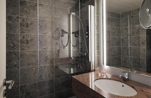 a bathroom with a sink and a shower at Leonardo Royal Hotel Düsseldorf Königsallee in Düsseldorf