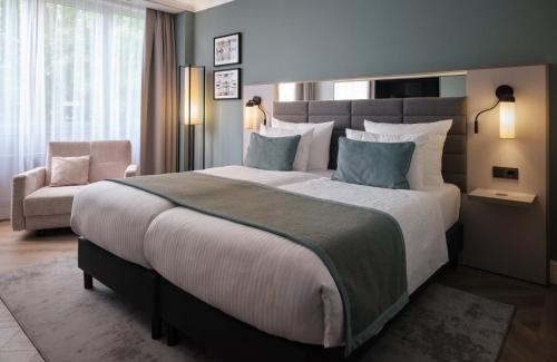 a bedroom with a large bed and a chair at Leonardo Royal Hotel Düsseldorf Königsallee in Düsseldorf