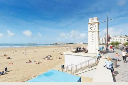 une tour d'horloge sur une plage avec une foule de gens dans l'établissement Pleasant seaside studio, à Les Sables-dʼOlonne