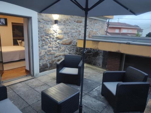 a patio with two chairs and an umbrella at Casa Capela1 in Folgosa